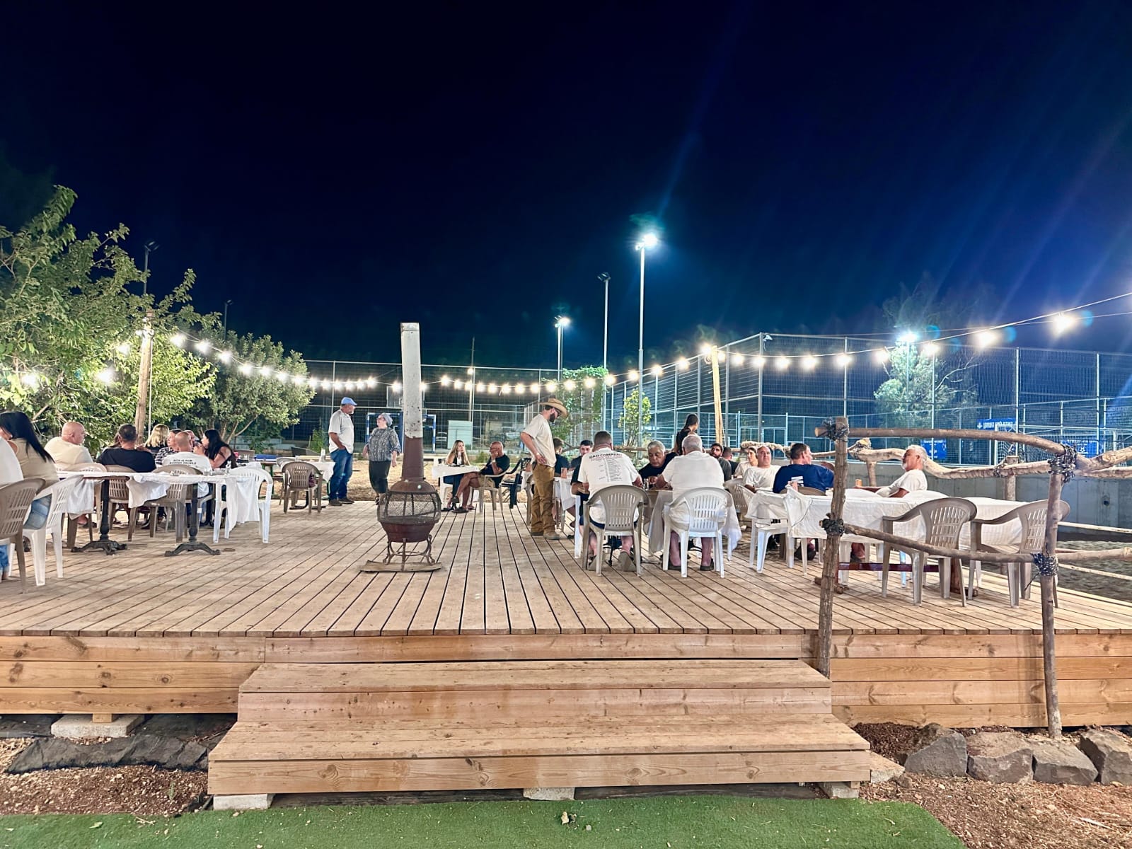 Guests dining on the wooden deck around the fire on an asado night