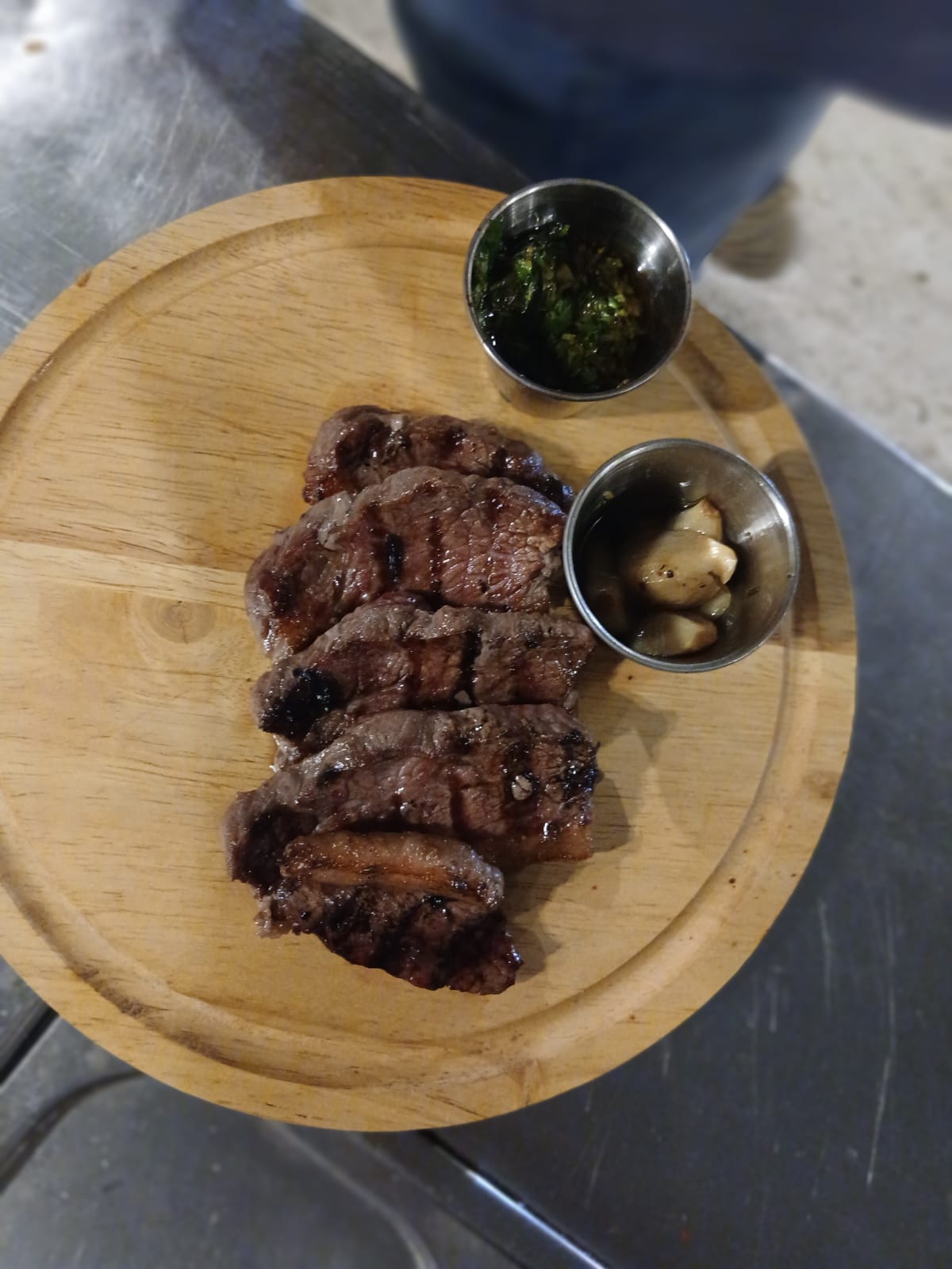 Sliced grilled steak with chimichurri and confit garlic
