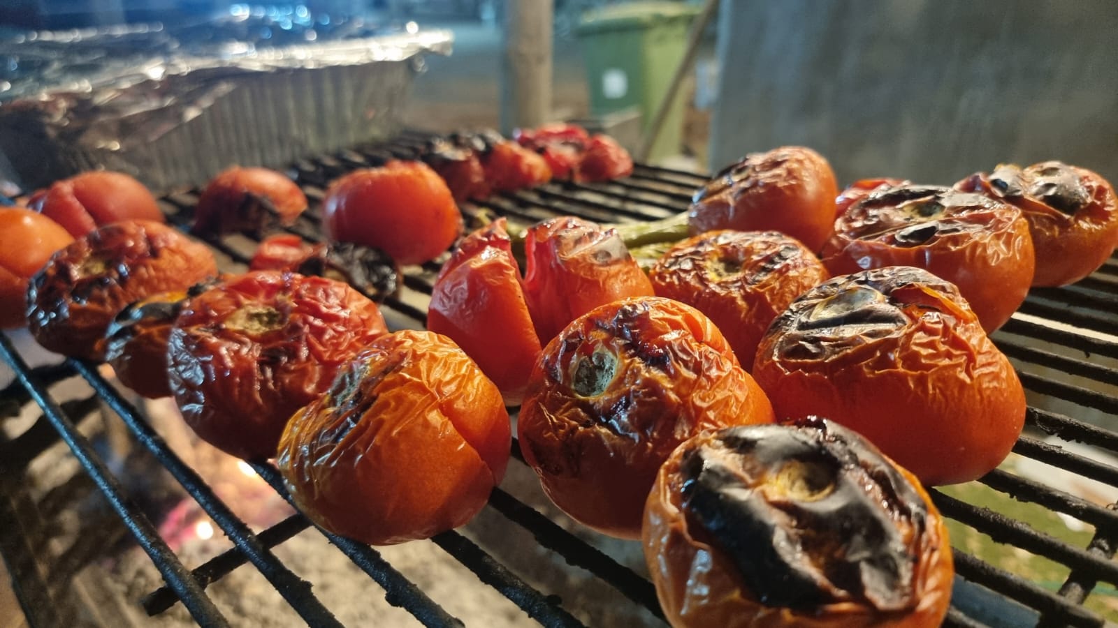 Whole tomatoes grilling over the coals